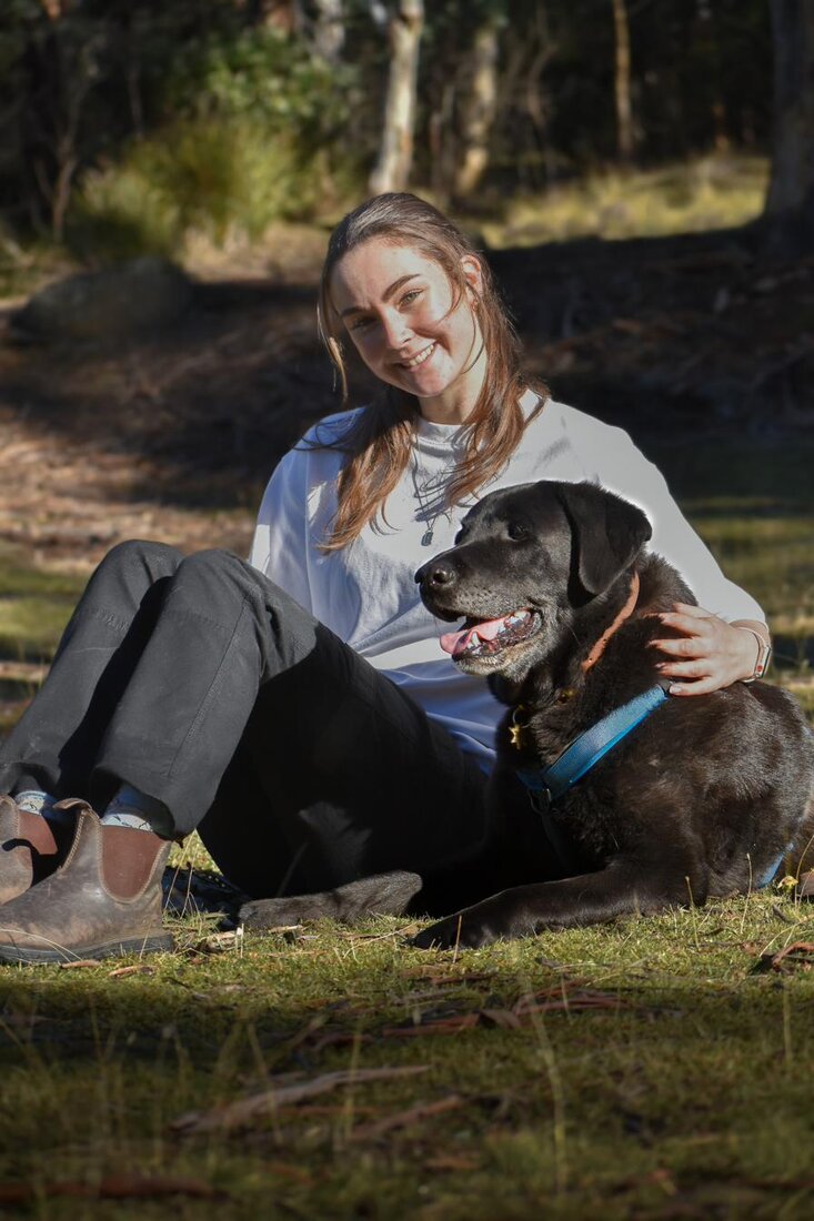 Sophie sitting in golden evening light with her black Labrador