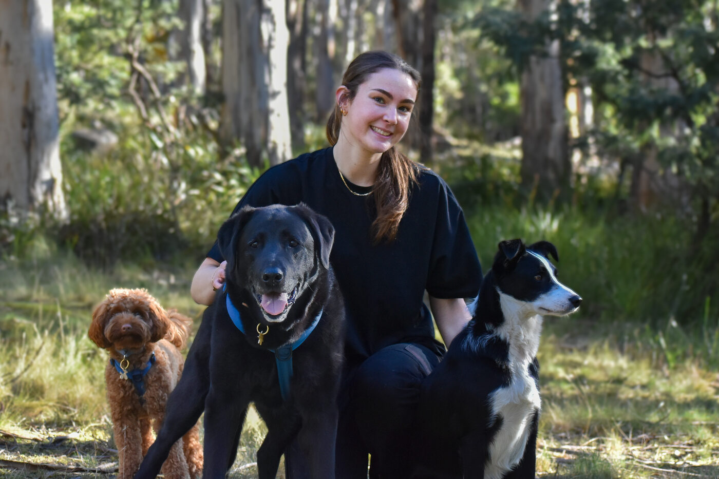 Sophie with three happy dogs in the Tasmanian bush